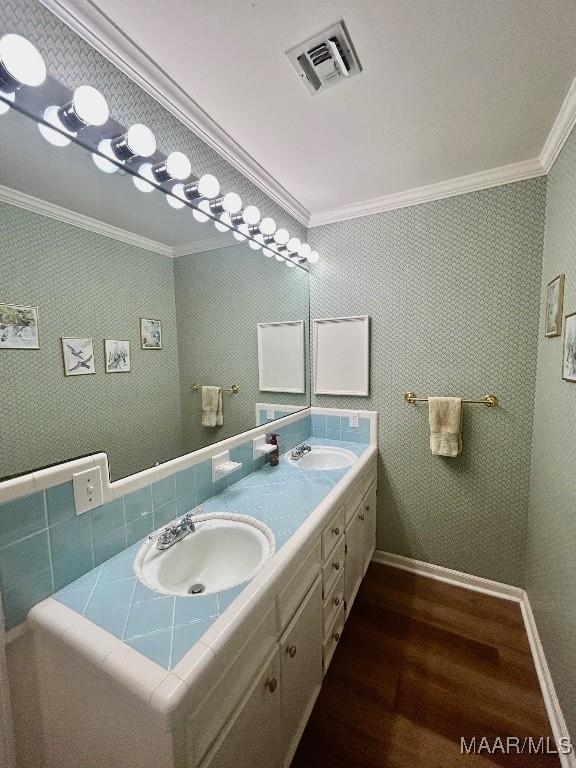 bathroom featuring crown molding, a sink, wood finished floors, and visible vents