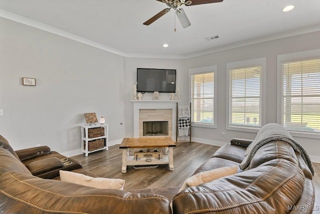 living area with crown molding, a ceiling fan, baseboards, and visible vents