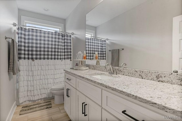 bathroom with vanity, toilet, a shower with shower curtain, baseboards, and wood finished floors