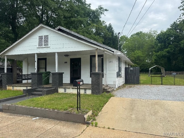 bungalow-style home featuring fence, a porch, and a front lawn