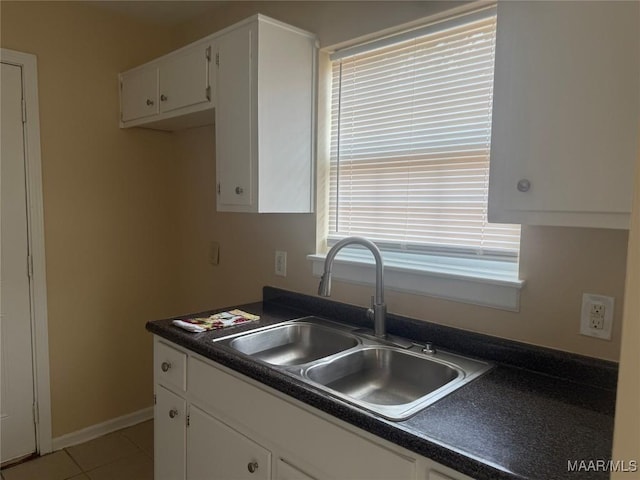 6253 S Hampton Dr, Montgomery, AL 36116 - kitchen with white cabinets, light tile patterned flooring, dark countertops, a sink, and baseboards