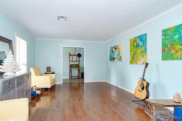 living area featuring baseboards, ornamental molding, wood finished floors, and visible vents