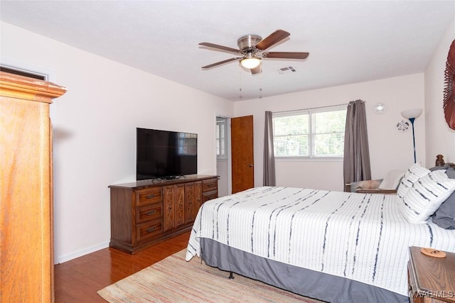 bedroom with baseboards, a ceiling fan, wood finished floors, and visible vents