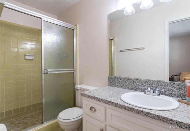 bathroom featuring vanity, a shower stall, and toilet
