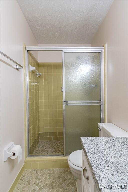 206 Choctaw Dr, Montgomery, AL 36117 - bathroom featuring tile patterned floors, toilet, a shower stall, and a textured ceiling