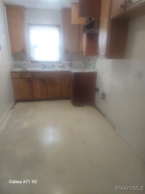 4709 S Court St, Montgomery, AL 36105 - kitchen featuring a sink, baseboards, brown cabinetry, and light countertops