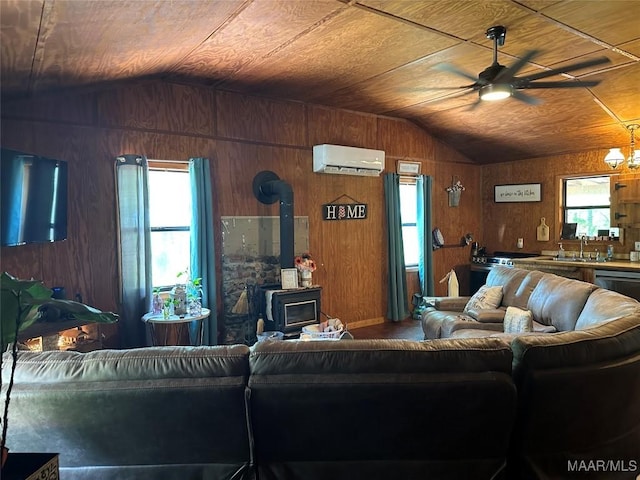living room featuring a wood stove, ceiling fan, a wall unit AC, and vaulted ceiling