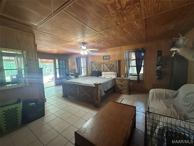 bedroom with wooden walls, tile patterned floors, attic access, and access to exterior