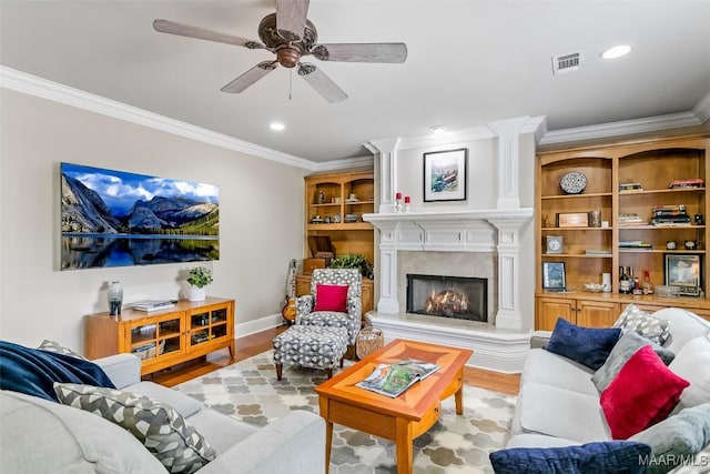 living area featuring ornamental molding, wood finished floors, and a high end fireplace