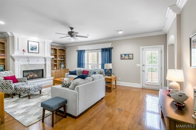 living area featuring a ceiling fan, a wealth of natural light, light wood-style flooring, and a high end fireplace