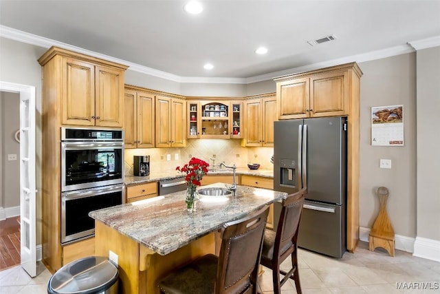 kitchen with visible vents, appliances with stainless steel finishes, a sink, baseboards, and light stone counters