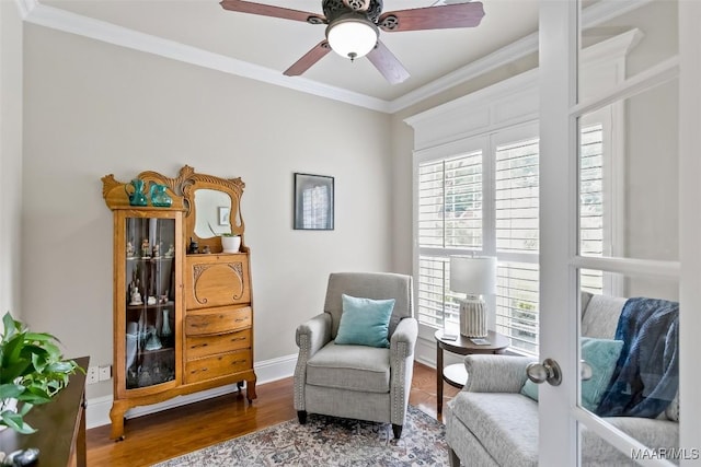 living area with baseboards, ornamental molding, a ceiling fan, and wood finished floors