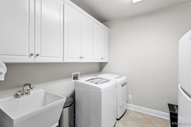 laundry room featuring washing machine and clothes dryer, cabinet space, a sink, baseboards, and light tile patterned floors