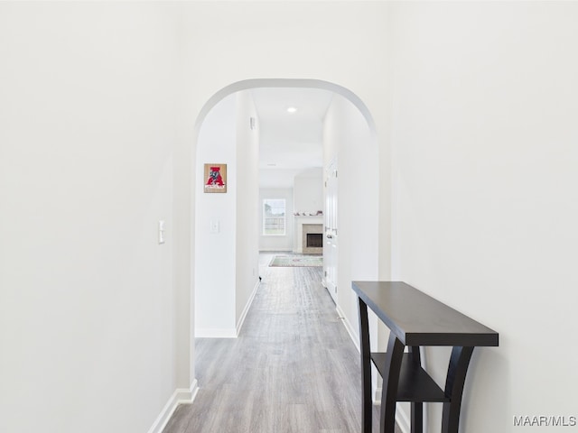 corridor with baseboards, arched walkways, and wood finished floors