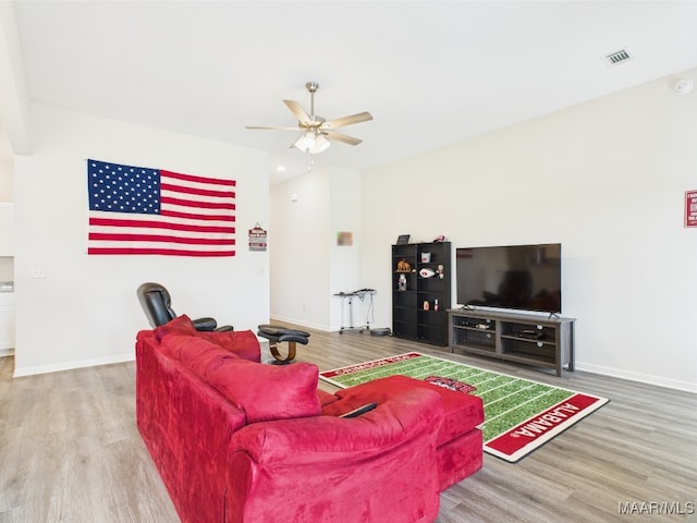 living room featuring baseboards, a ceiling fan, wood finished floors, and visible vents