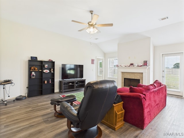 living room featuring a ceiling fan, vaulted ceiling, wood finished floors, and visible vents