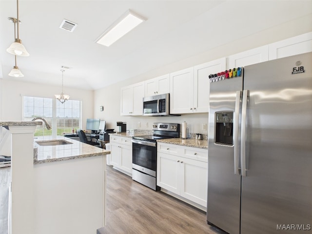 kitchen with visible vents, a sink, lofted ceiling, stainless steel appliances, and white cabinetry