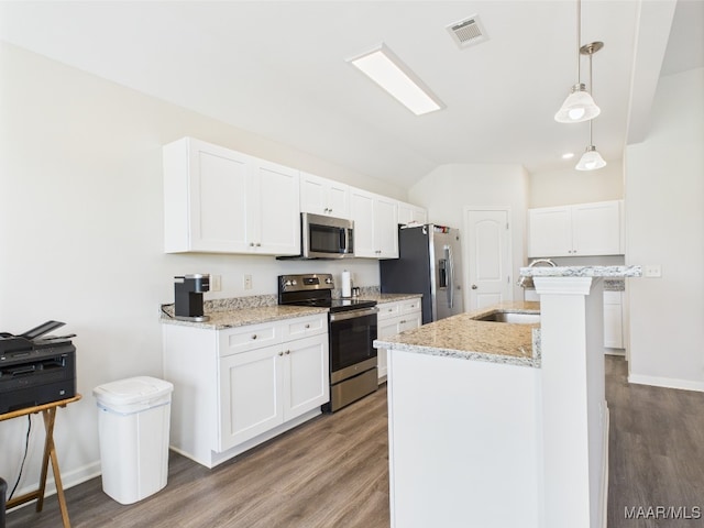 kitchen featuring vaulted ceiling, stainless steel appliances, wood finished floors, and visible vents