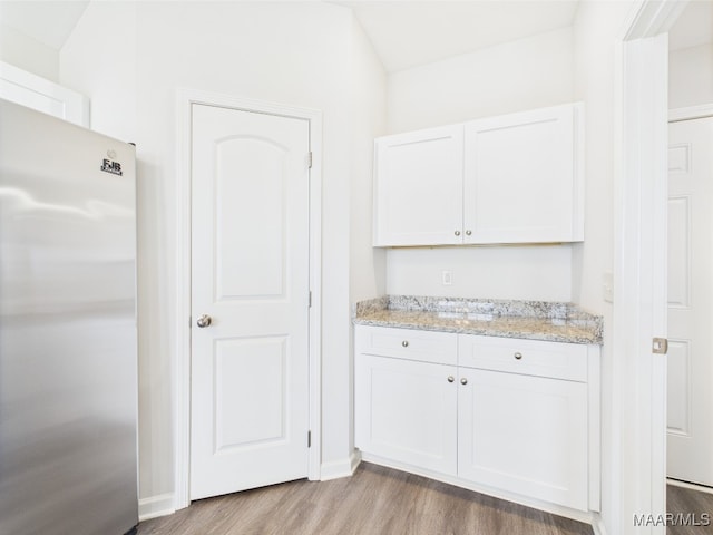 interior space with baseboards, freestanding refrigerator, and wood finished floors