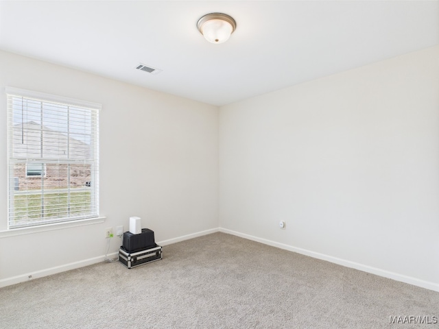 spare room with carpet flooring, baseboards, and visible vents