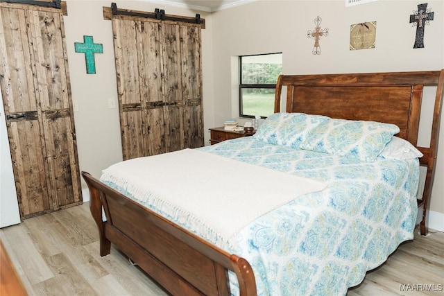 2755 Cherokee Trl, Tallassee, AL 36078 - bedroom featuring crown molding, a barn door, and light wood-style floors