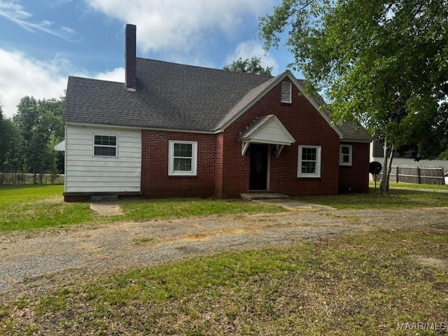 view of front facade featuring roof with shingles, fence, and a front yard