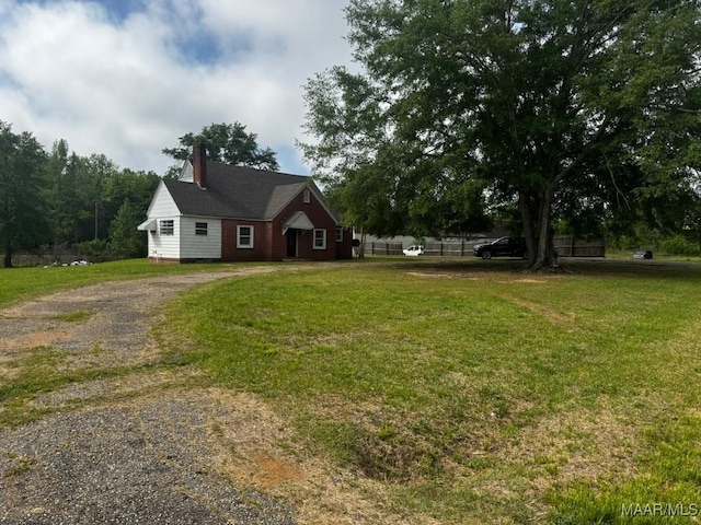 view of front of property featuring a chimney, a front lawn, and gravel driveway
