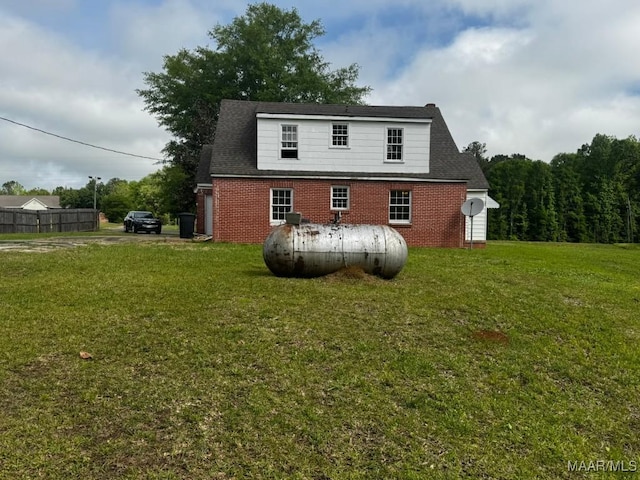 back of house featuring brick siding and a lawn