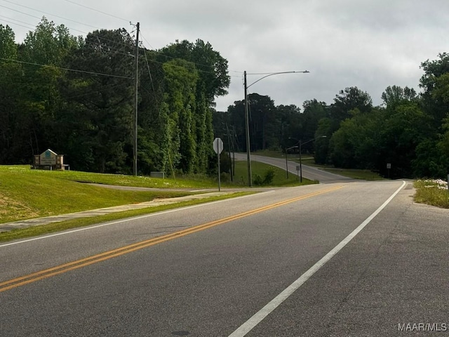 view of street featuring traffic signs, street lighting, and a forest view