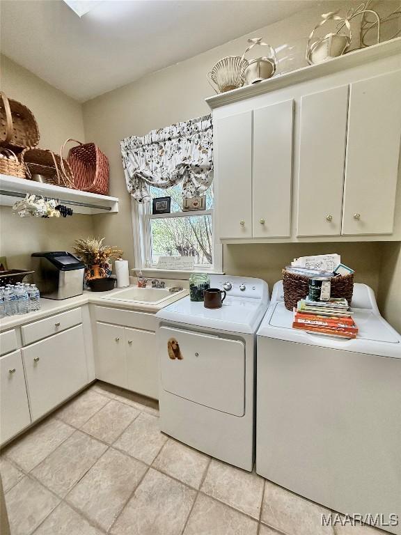 laundry area with a sink, cabinet space, light tile patterned flooring, and washer and clothes dryer