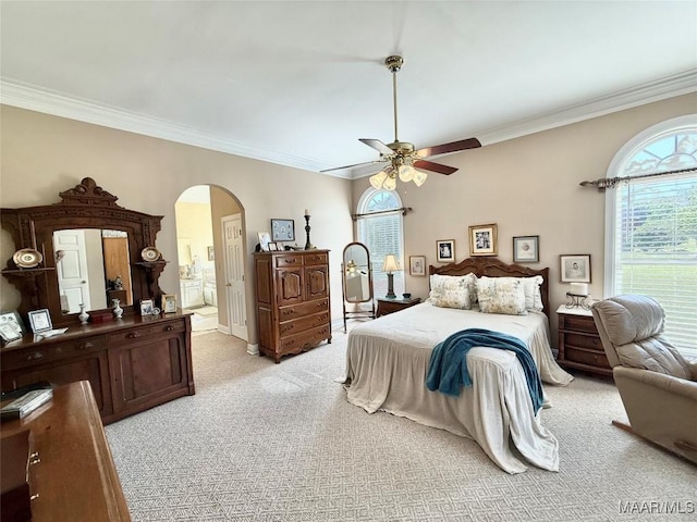 bedroom with ceiling fan, crown molding, arched walkways, ensuite bathroom, and light carpet