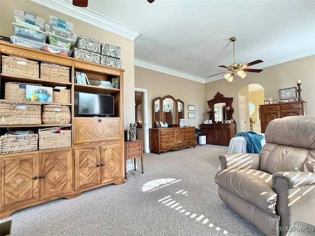 living area with arched walkways, ceiling fan, light carpet, and ornamental molding