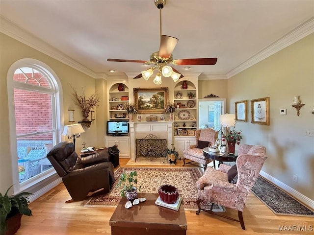 living area featuring ornamental molding, a healthy amount of sunlight, and light wood-style floors