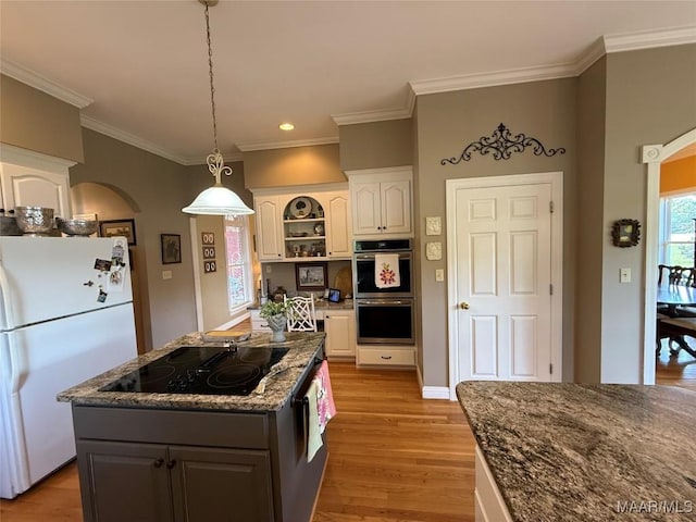 kitchen with freestanding refrigerator, light wood-type flooring, stainless steel double oven, black electric cooktop, and white cabinets