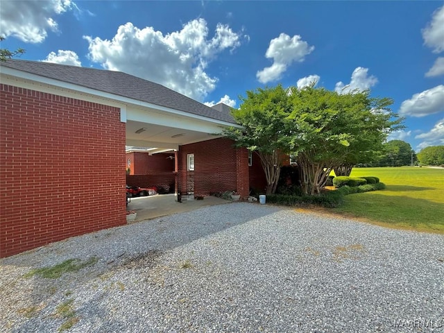 view of home's exterior featuring brick siding, a yard, and driveway