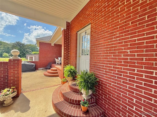 view of property exterior with a patio area and brick siding