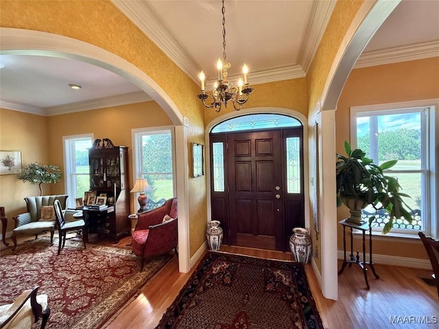 foyer featuring arched walkways, ornamental molding, and wood finished floors