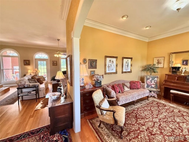 living room featuring ornamental molding, a ceiling fan, and wood finished floors