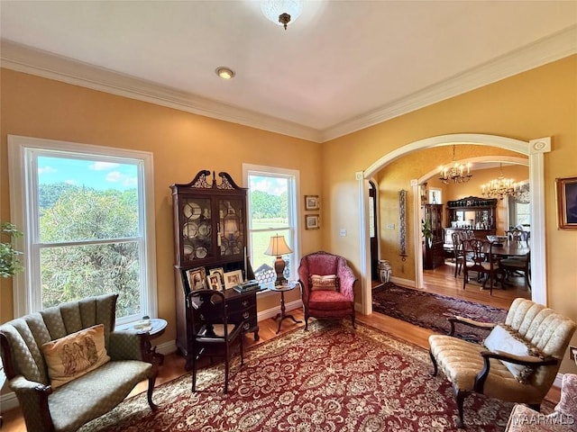 sitting room featuring crown molding, arched walkways, wood finished floors, and an inviting chandelier
