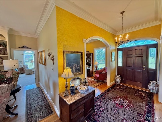 foyer with crown molding, arched walkways, and plenty of natural light