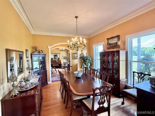 dining room with light wood-style floors, crown molding, and a notable chandelier