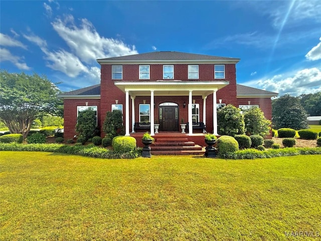 back of property with a lawn, covered porch, and brick siding