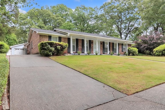 view of front of property with a porch, driveway, an outbuilding, brick siding, and a front lawn