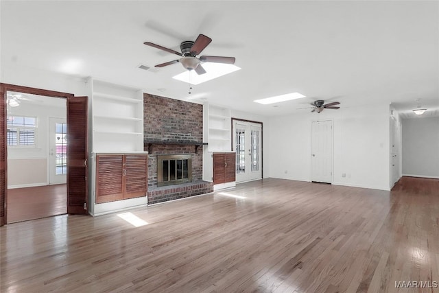 unfurnished living room featuring baseboards, built in features, ceiling fan, and wood finished floors