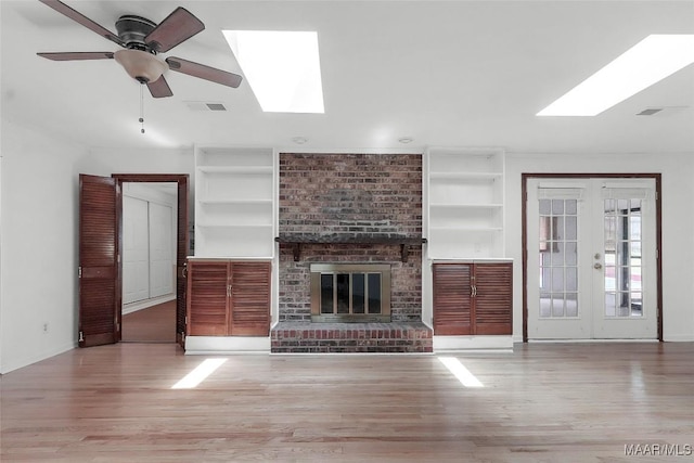 unfurnished living room featuring ceiling fan, french doors, wood finished floors, a skylight, and visible vents