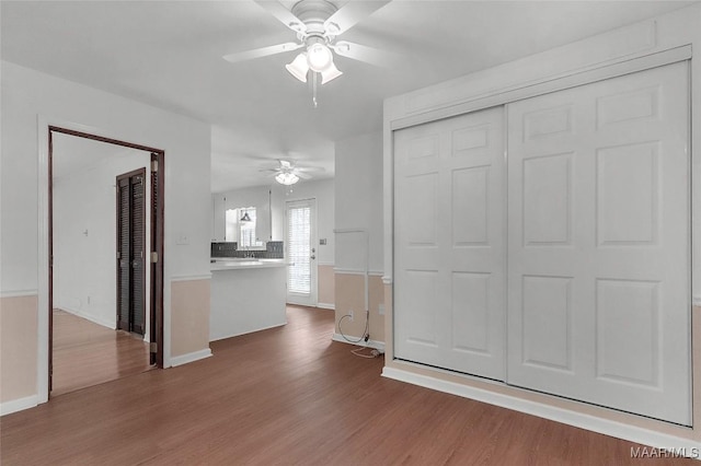 unfurnished living room with baseboards, ceiling fan, and wood finished floors