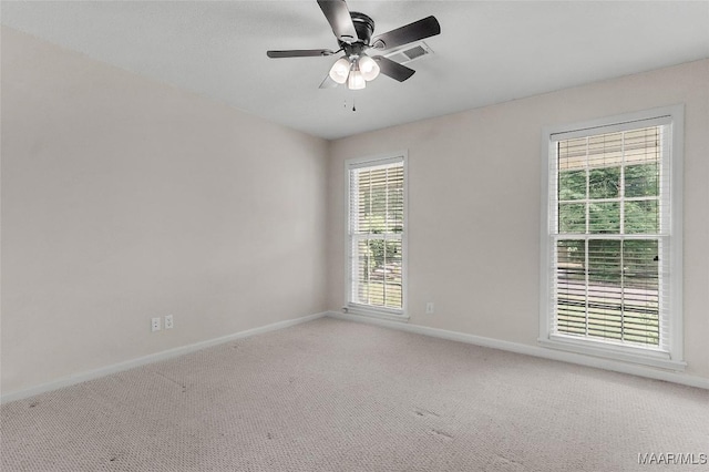 spare room with baseboards, ceiling fan, light carpet, and visible vents