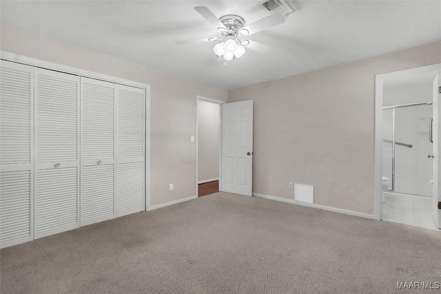 unfurnished bedroom with a closet, carpet flooring, baseboards, and ensuite bath