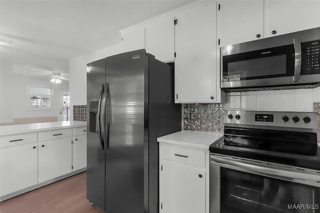 kitchen with light countertops, appliances with stainless steel finishes, white cabinets, and backsplash