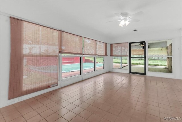 unfurnished sunroom featuring visible vents, a ceiling fan, and tile patterned floors